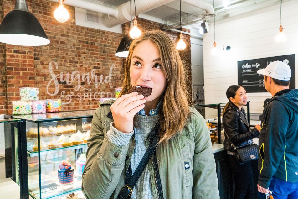 A woman eats a cookie in a dessert shop