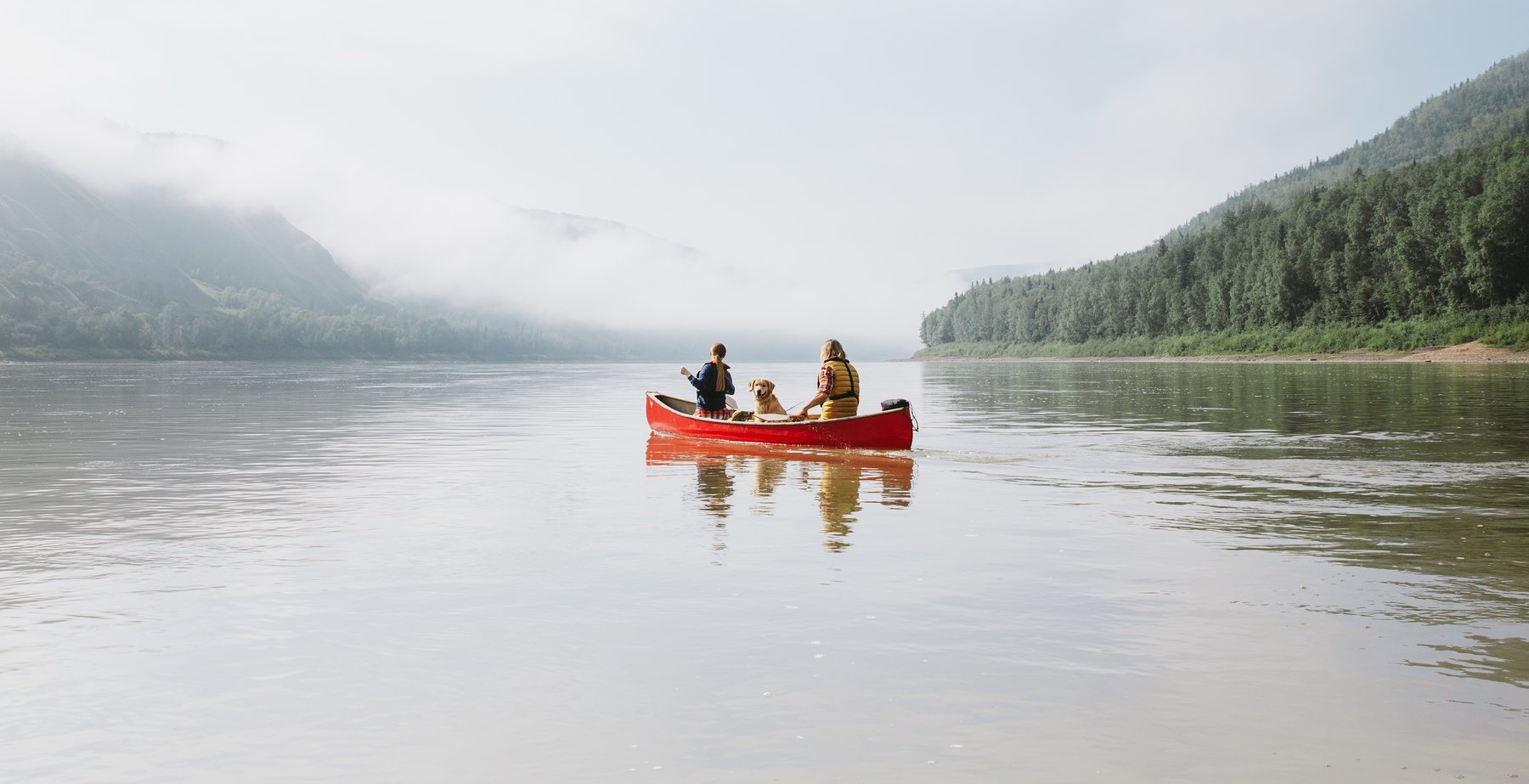 Couple with dog paddling canoe in Peace River