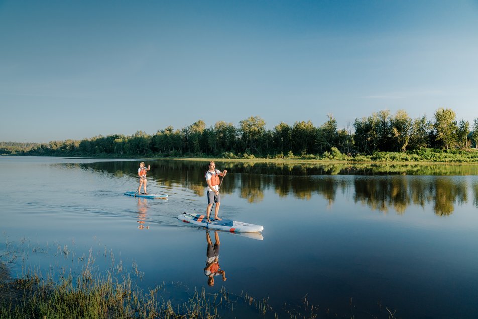 Two people on stand up paddle boards on Syne River near Fort McMurray.