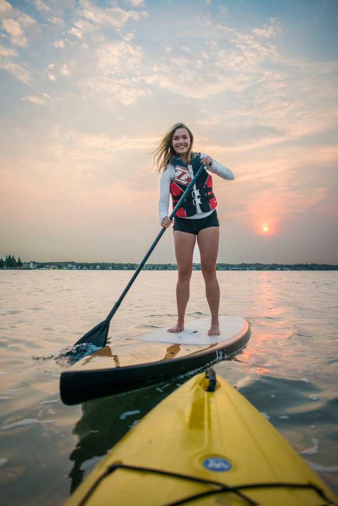 Woman stand-up paddleboarding with the sun going down