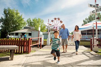 Family at Heritage Park with amusement rides behind them