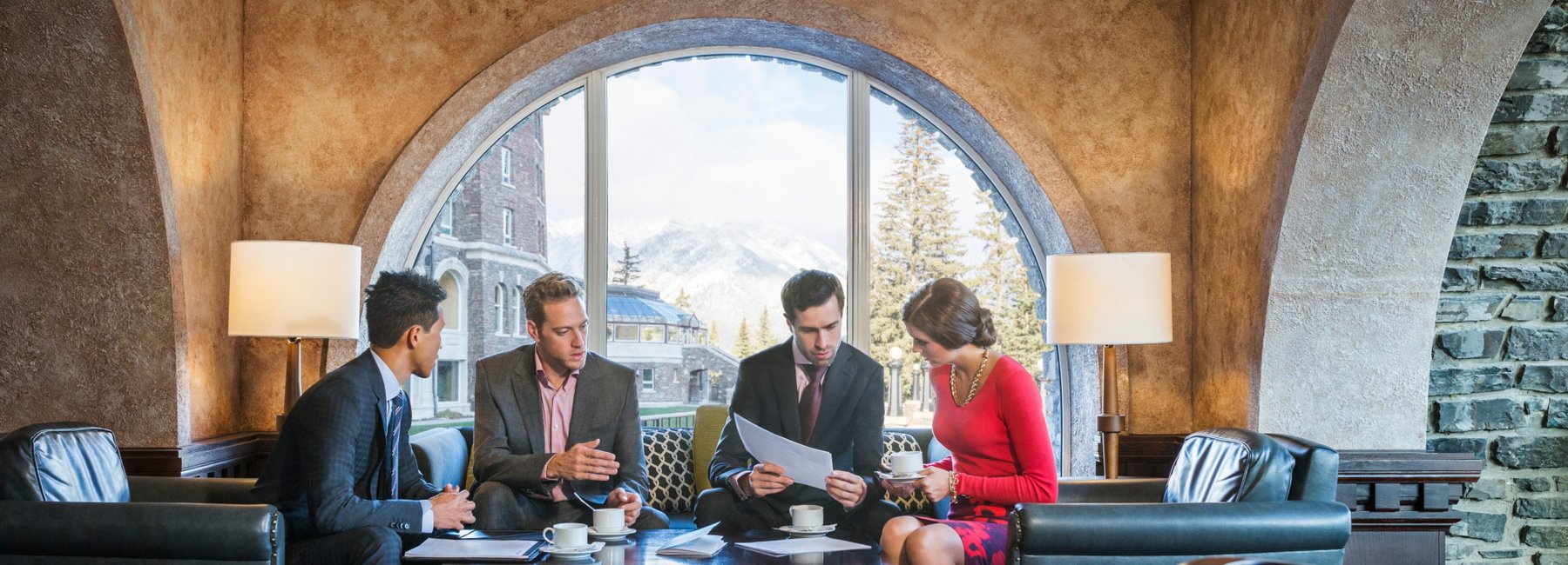 Group of four sitting and discussing business over coffee, Fairmont Banff Springs Hotel.