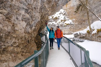 A couple walking the steel catwalk during a winter hike at Johnston Canyon in Banff.