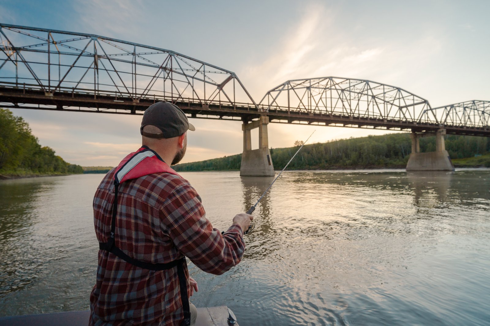 Man fly fishing on the Peace River with a bridge in the background.