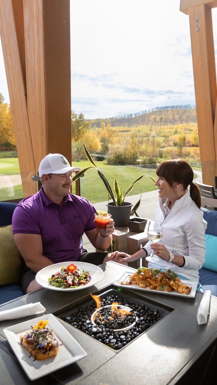 Two golfers sitting on a patio and enjoying lunch at Fort McMurray Golf Club's clubhouse.