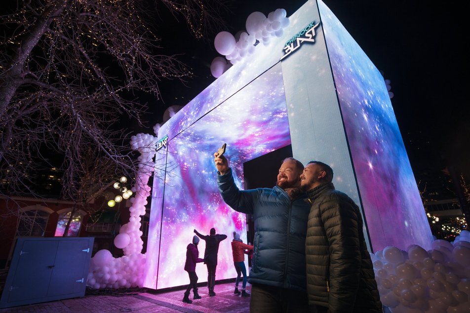 Two people take a selfie in front of a light display at Chinook Blast in Calgary.