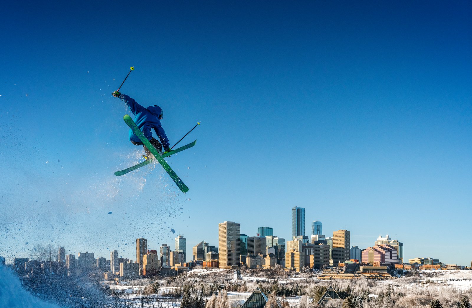 Person ski jumping with downtown Edmonton in background.
