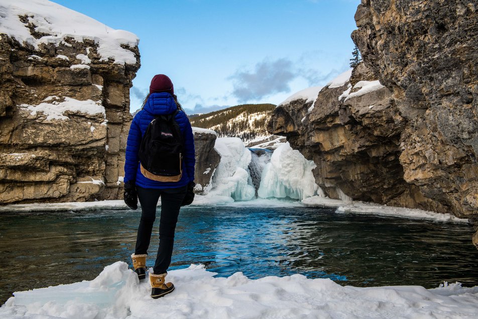 A hiker stops to admire the frozen waterfall at Elbow Falls in Bragg Creek