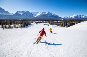 Two people skiing down an intermediate run at Lake Louise Ski Resort in Banff National Park.