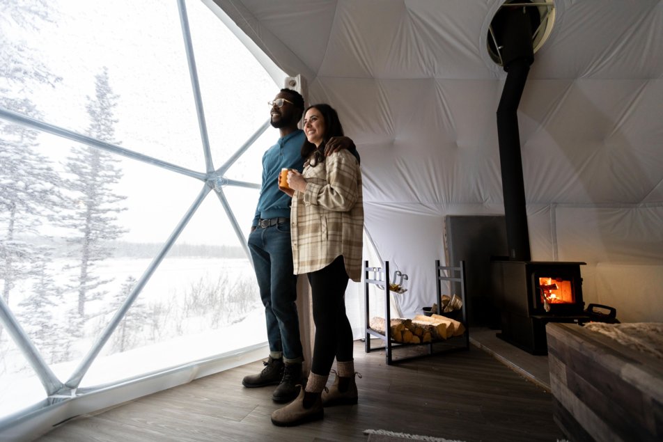 Couple standing by window inside of dome tent with Elevated Escapes