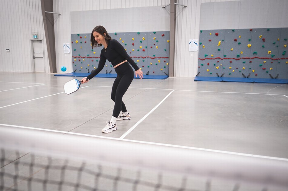 Woman playing pickleball indoors.