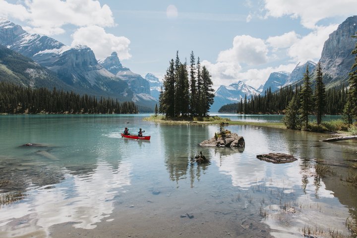 Scenic shot of two people in a red canoe on Maligne Lake with mountains in the background