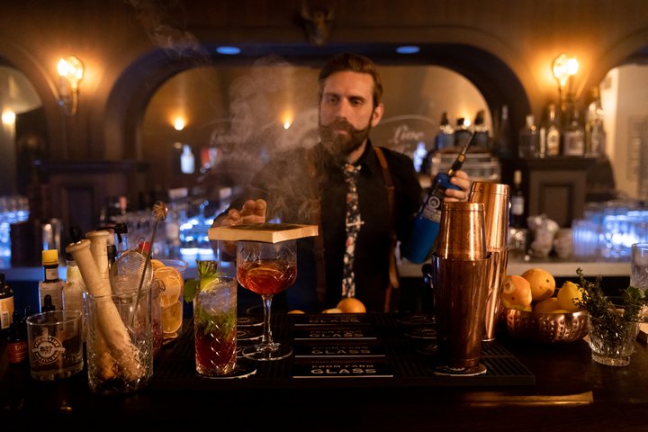 Mixologist smoking a cocktail at Eau Claire Distillery Speakeasy.