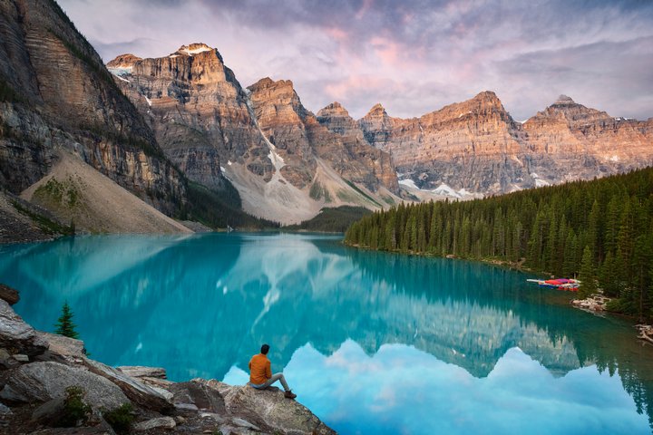 Person sitting on rocks overlooking the mountain view at Moraine Lake