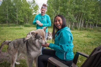 Two women smiling and feeding wolfdogs at Yamnuska Wolfdog Sanctuary.