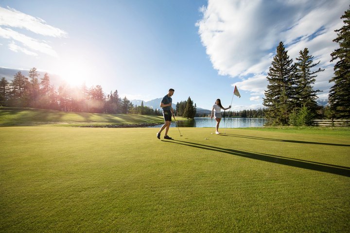 A man and woman golf at the Fairmont Jasper Park Lodge golf course.