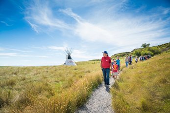 School group walking the pathways at Head-Smashed-In Buffalo Jump with an Indigenous guide.