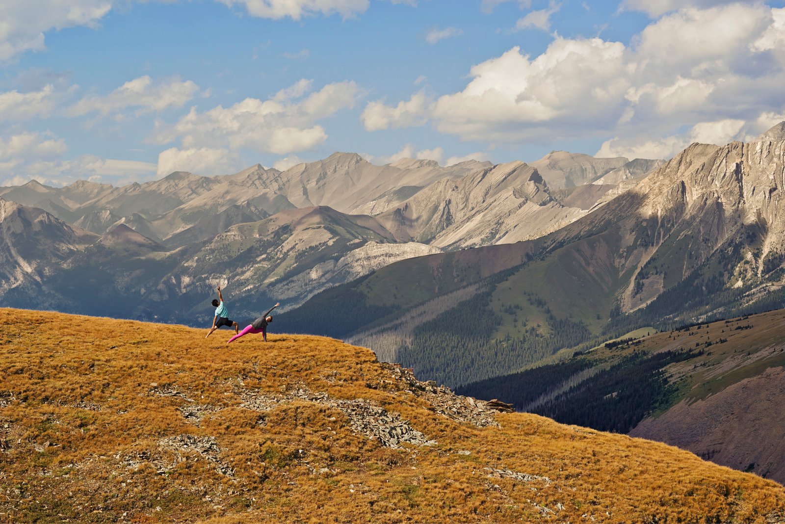 Male and Female doing yoga in front of mountains