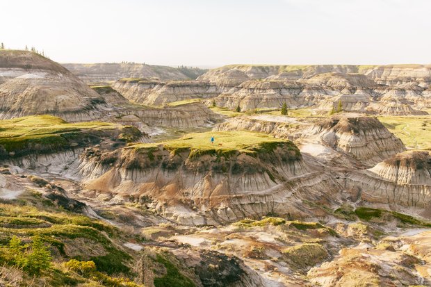 Person and their dog hiking in the badlands amongst epic hoodoos on a summer day