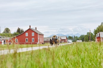 A covered wagon travels along the road at Bar U Ranch National Historic Site.