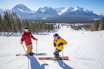 Two skiers take a break mid-mountain before skiing at Lake Louise Ski Resort in Banff National Park