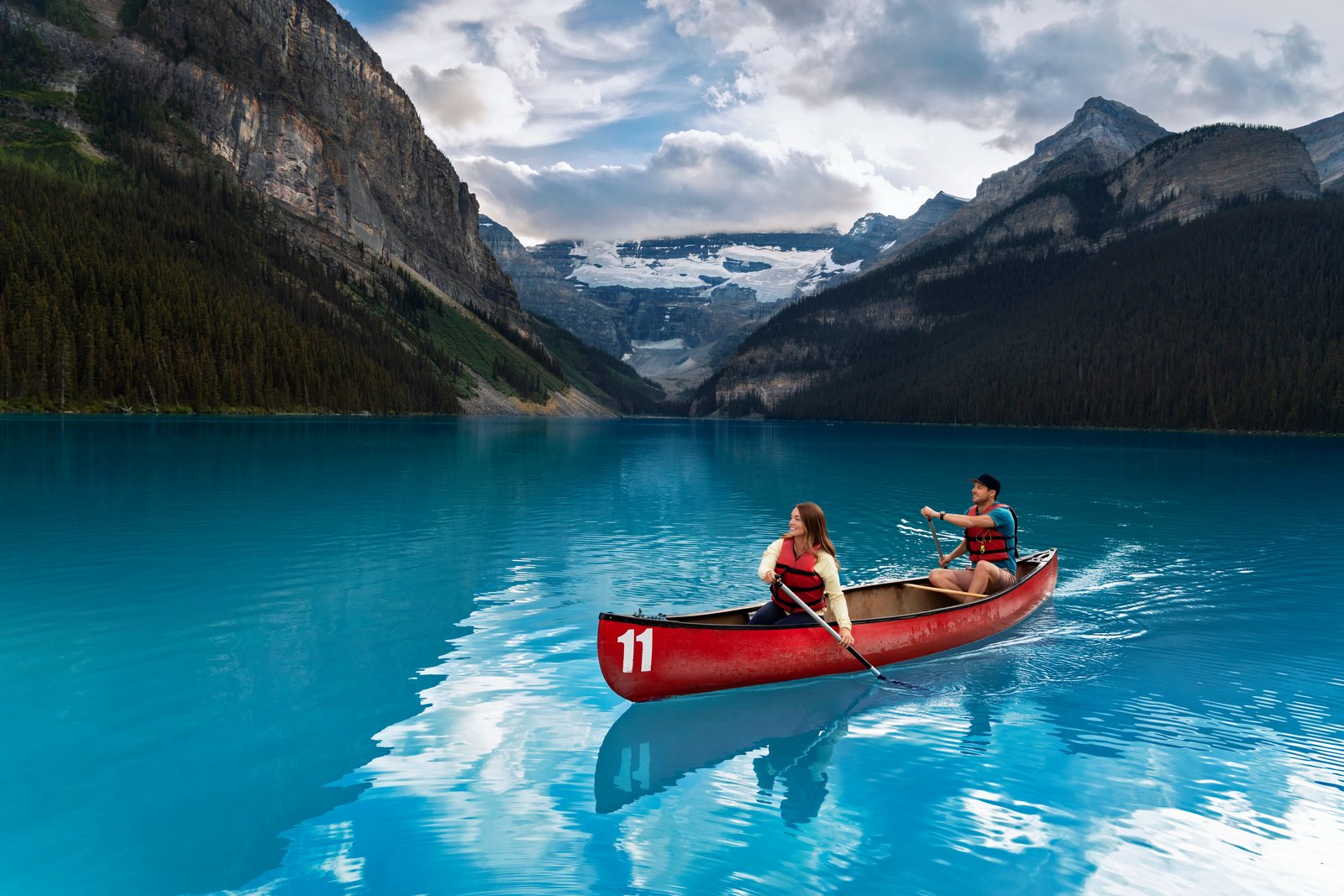 Couple canoeing, surrounded by mountains at Lake Louise in Banff National Park.