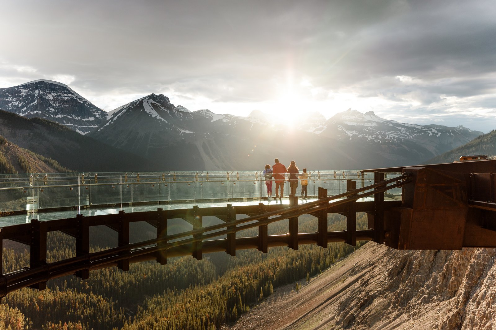 Family standing on the Columbia Icefield Skywalk watching the sunset.
