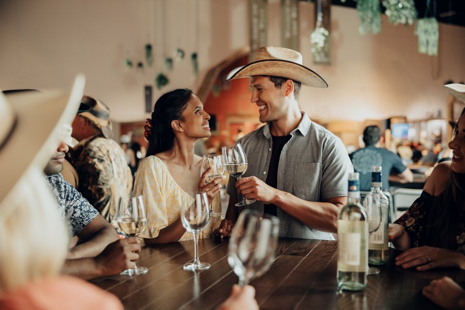 Couple having wine at a bar with people.