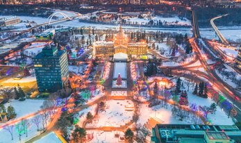 A view from above of the snow-covered Alberta Legislature Grounds sprinkled with holiday lights and the warm glow of sundown.