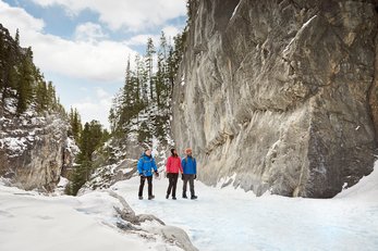 A group of three people ice walking and hiking through Grotto Canyon near Canmore in Kananaskis Country.