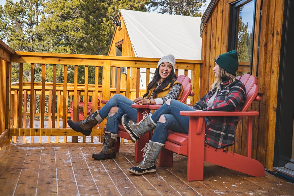 Friends sitting on the porch while winter camping at Mount Engadine Lodge in Kananaskis Country.