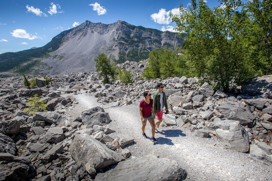 A couple explores a trail surrounded by the massive boulders from the disastrous Frank Slide.