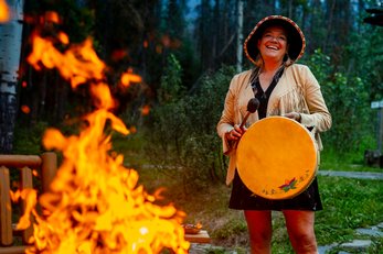 Warrior Woman Matricia Brown striking a drum next to a bonfire