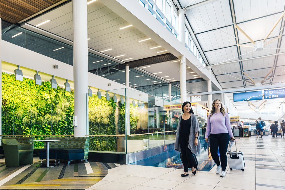 Two women walking with luggage through an airport