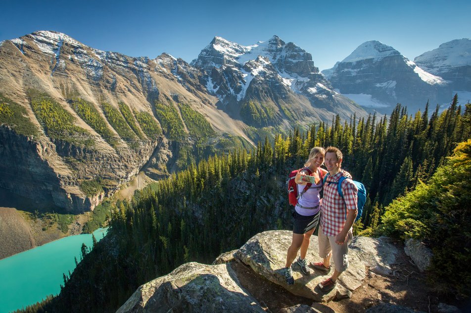 Couple taking a photo at Little Beehive on the trail to the Lake Agnes Tea House in Banff National Park.