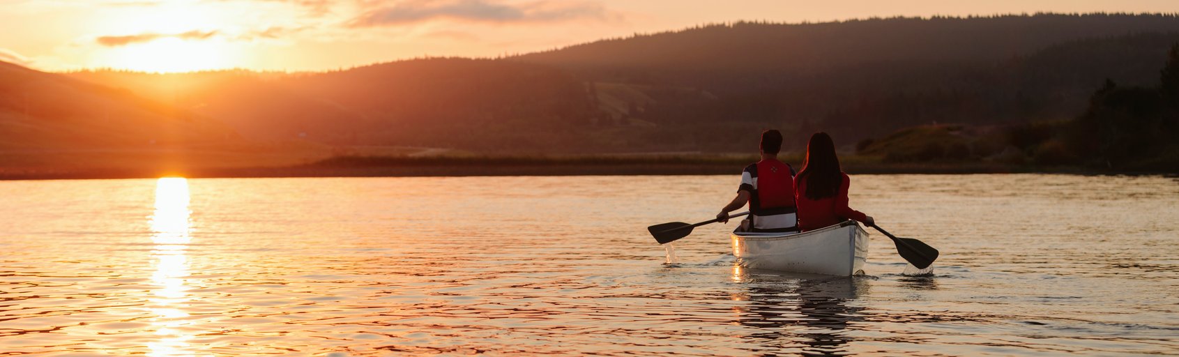 Couple canoeing on Cypress Lake at sunrise.