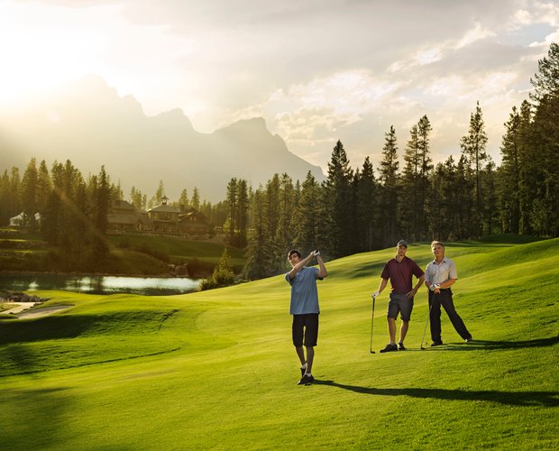 Three men on the green golfing at the Canmore Silvertip Golf Course in the Canadian Rockies.
