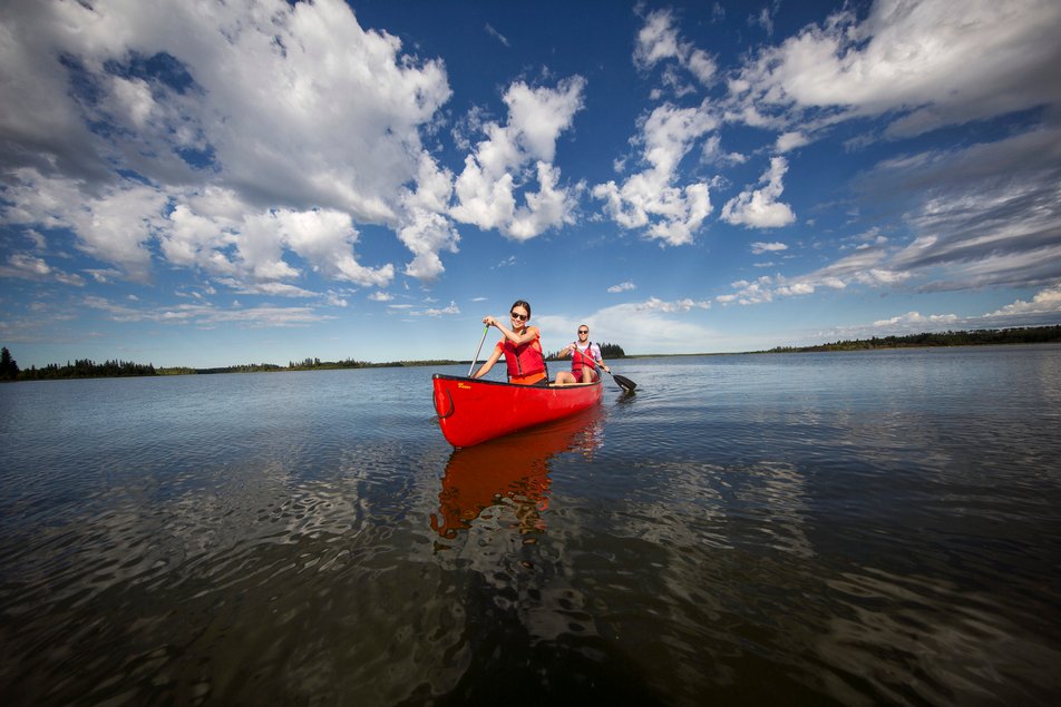 Couple paddling a red canoe on a lake