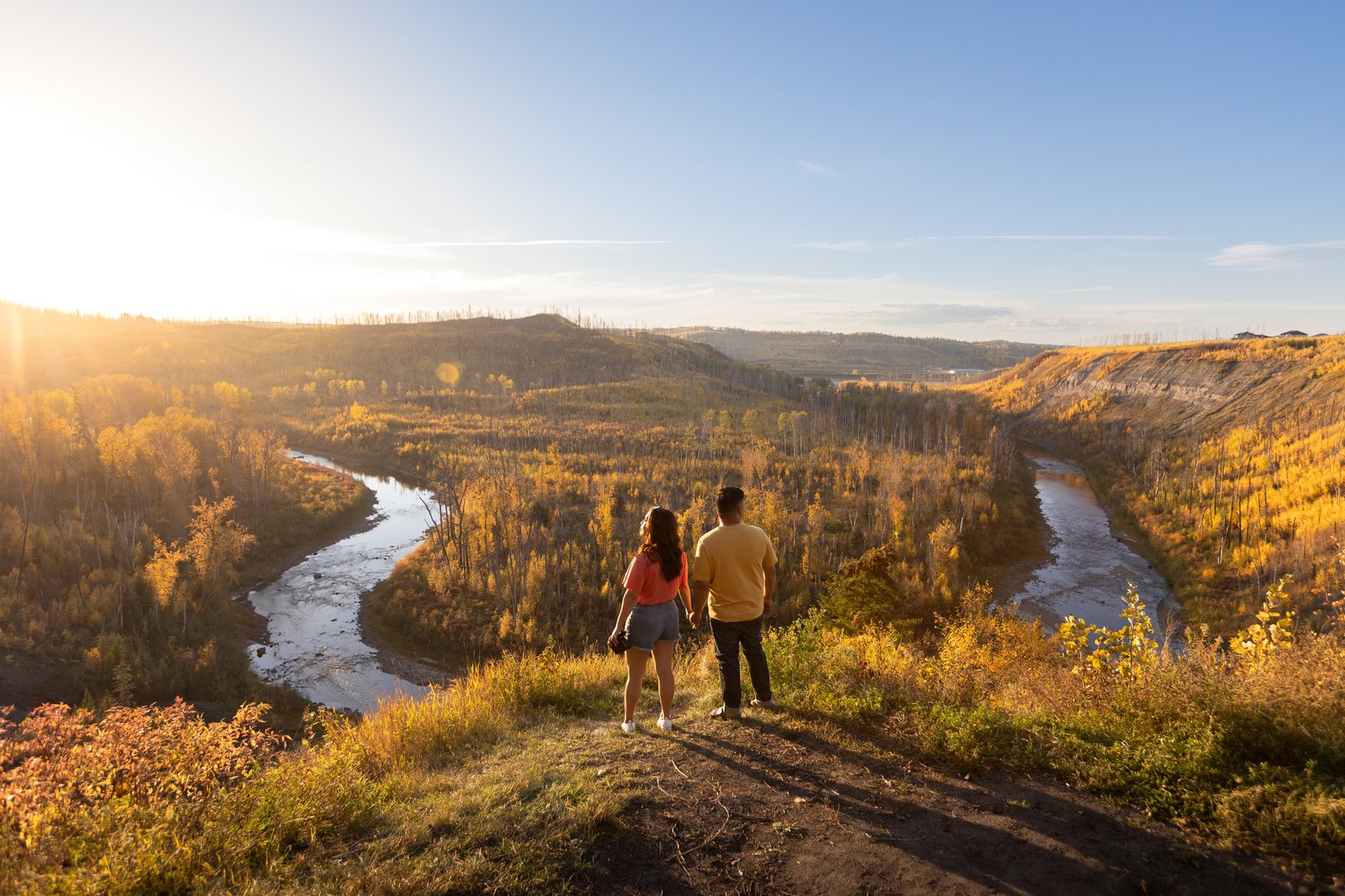 Two people looking over river lookout and the autumn trees during a sunset.