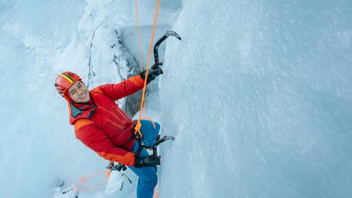 An ice climber climbing up a frozen waterfall.