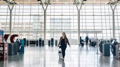 Woman walking with luggage through airport terminal