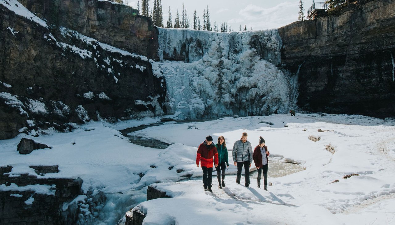 A family enjoys the frozen waterfall at Crescent Falls in Clearwater County, Nordegg