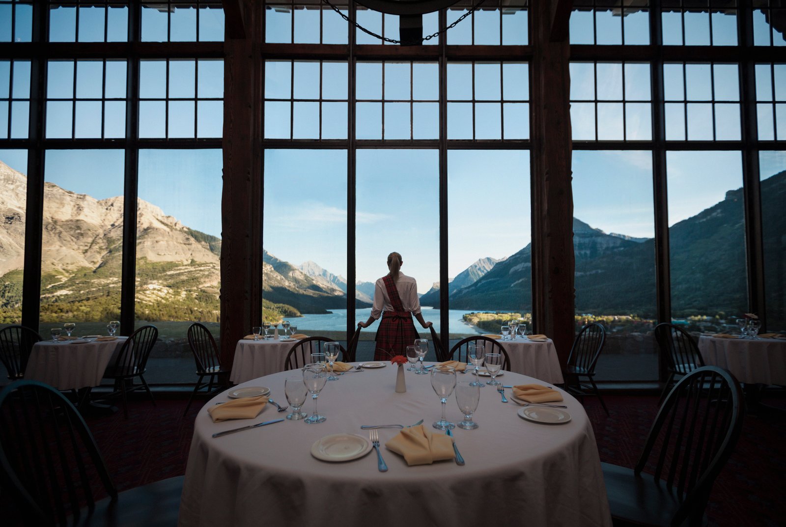 Waitress looking out restaurant windows to the lake at the Price of Wales Hotel in Waterton.