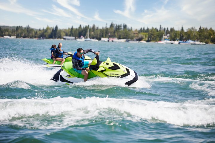 Two people making waves on green jet skis on Sylvan Lake.