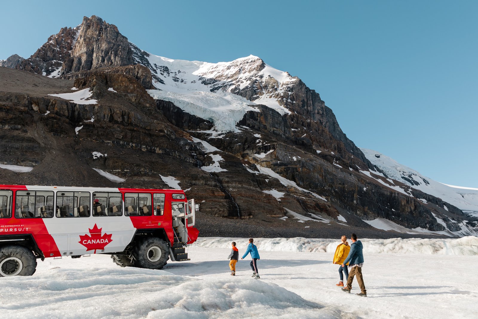 A family of four walking towards a bus on a Columbia Icefield Glacier tour.