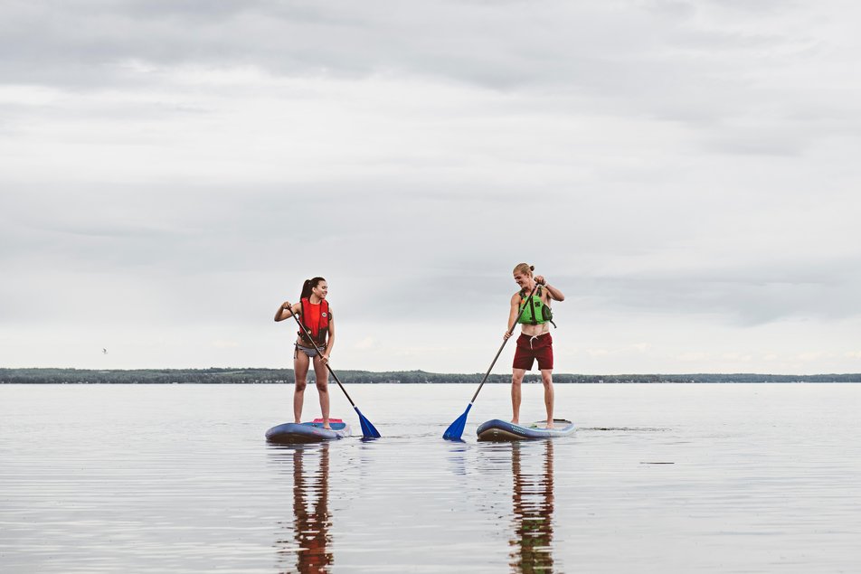 A couple of paddleboarders paddle on the calm waters of Pigeon Lake.