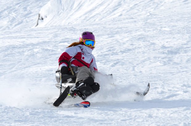 A sit skier carves it up while skiing.