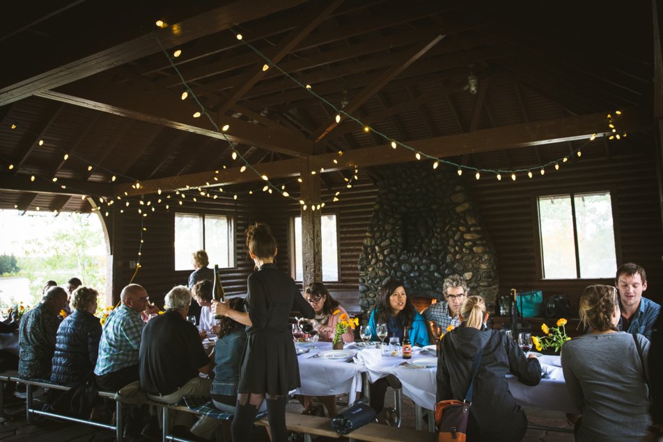 People dining in a log cabin at an Elk Island National Park dinner event with Kitchen by Brad.
