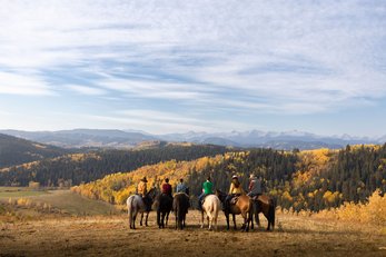 A group of people on a trail ride in the foothills.