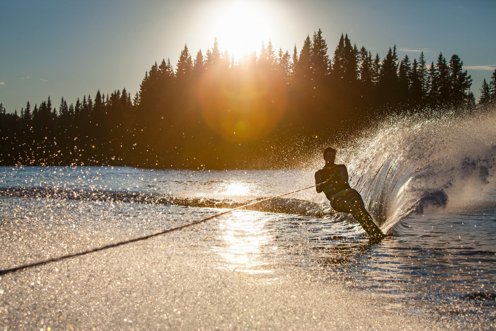 Man wakeboarding splashing up water at sunset on Island Lake.